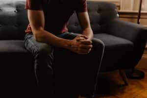 Man sitting on a couch with hands clasped