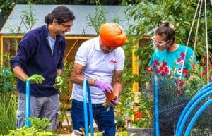 3 njerëz që bëjnë disa kopshtari në një pjesë për projektin e recetave sociale të gjelbërta