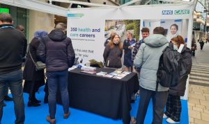 Photograph of people at a stall at a NHS careers event.